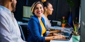 woman on laptop smiling at coworker